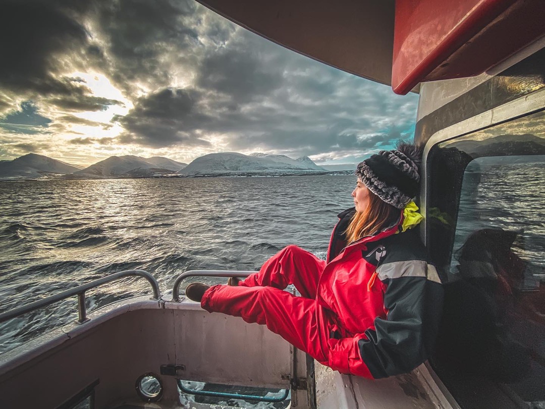 Red windbreaker against a storm-grey fjord